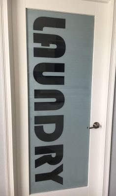 Frosted glass custom laundry door with clear letters.